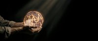 Hands holding glowing geometric sphere with intricate polygonal pattern against dark background. Futuristic technology concept for innovation and digital transformation.