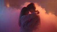 Romantic couple silhouette embracing in dramatic colorful smoke clouds with purple and orange lighting for love and relationship concepts.