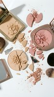 Broken makeup powder compacts and brushes scattered on white background creating artistic beauty product flatlay for cosmetic advertising and fashion content.