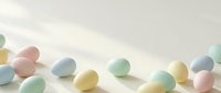Colorful pastel Easter eggs scattered on white surface with soft natural lighting creating gentle shadows for spring holiday celebrations and decorations.
