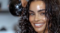 Young African American woman with wet curly hair and bright smile showing glowing, hydrated skin and natural beauty. Wellness and skincare concept.