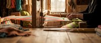Traditional wooden loom with colorful threads in rustic workshop setting. Artisan hands weaving textile craft in warm sunlit interior for handmade production.