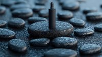 Black spa stones with water drops arranged in pattern with aromatherapy oil dropper, creating zen-like atmosphere for wellness and relaxation background.