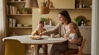 Young mother with two toddlers enjoying healthy meal together at modern kitchen table in warm cozy home interior for family lifestyle content.