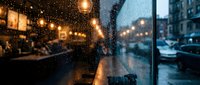 Cozy cafe interior with warm lighting and raindrops on window glass creating atmospheric evening ambiance for hospitality and lifestyle concepts.