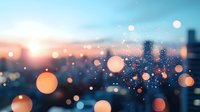 Dreamy urban bokeh lights against twilight cityscape with soft orange and blue tones creating atmospheric blur effect for background designs.
