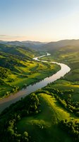 Aerial view of winding river flowing through lush green valley with forested hills and mountains at golden hour, suitable for travel and nature backgrounds.