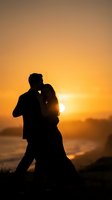 Romantic couple silhouette embracing at golden sunset by ocean beach creating intimate moment against warm orange sky for wedding anniversary concepts.