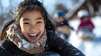 Young Asian girl laughing joyfully while playing in snow, wearing warm winter coat and fur collar. Natural outdoor lighting captures authentic happiness during winter activities.