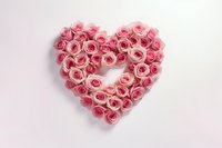 Pink roses arranged in heart shape on light background, romantic floral composition for wedding, Valentine's Day, and anniversary celebrations.