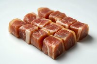 Raw cubed pork belly with visible fat layers arranged in neat rows on white background, fresh meat cut for cooking Asian and European cuisine recipes.
