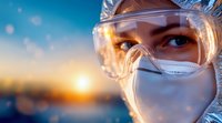 Medical professional wearing protective goggles and N95 mask looks toward sunset, close-up view of determined eyes reflecting hope and resilience during healthcare crisis.