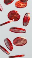 Red transparent plastic tokens falling on white background, dynamic composition with floating circular game pieces showing depth and motion in casino style layout.