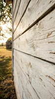 Weathered white wooden siding with peeling paint on rustic barn wall, rural farmhouse exterior architecture with natural aging and vintage charm.