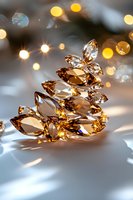 Sparkling amber crystals arranged in Christmas tree shape with golden bokeh lights and soft shadows on white surface, creating magical holiday atmosphere.