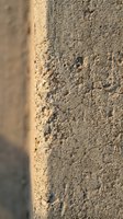Weathered concrete wall surface with rough textured finish showing natural aging and wear patterns for industrial construction backgrounds.