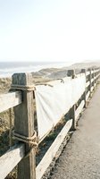 Coastal wooden fence with rope details leading to ocean beach landscape on overcast day for peaceful nature backgrounds.