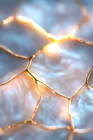 Glowing golden cracks on frosted surface create abstract pattern with warm light shining through crystalline texture against cool blue background.