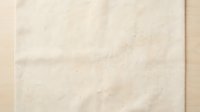 Vintage beige paper texture with natural aging marks and subtle stains creating authentic worn appearance for backgrounds and design projects.