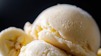 Creamy vanilla ice cream scoop with smooth swirls and rich texture against dark background, showcasing delicate details and soft shadows for food photography.