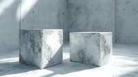 Two weathered concrete cubes sit on floor in minimalist interior with natural lighting and shadows creating modern architectural composition.