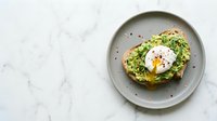 Avocado toast with poached egg on gray plate, marble background. Healthy breakfast, brunch, and food styling for culinary, recipe, and restaurant use.
