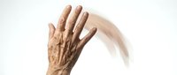 Elderly hand with motion blur effect showing a waving gesture against a white background, capturing movement and aging skin texture.