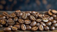 Fresh roasted coffee beans scattered on rustic wooden surface, macro shot showing rich brown color and natural texture of aromatic whole beans.