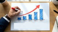 Business professional drawing red growth arrow on financial bar chart showing 5-year upward trend for corporate presentation and strategic planning.