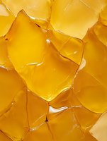 Golden amber broken glass fragments with sharp edges and reflective surfaces creating abstract geometric pattern for modern design projects.