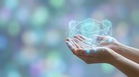 Digital cube hologram floating above open hands against blurred bokeh background, representing technology innovation, data protection, and future digital solutions for business and corporate applications.