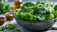 Fresh organic spinach leaves in ceramic bowl on kitchen counter for healthy cooking and salad preparation.