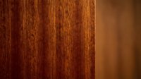 Rich mahogany wood grain texture with warm brown tones and natural vertical patterns for interior design and furniture applications.