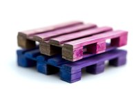 Colorful wooden shipping pallets in miniature size stacked together, featuring gradient pink to purple and deep blue tones against white background.