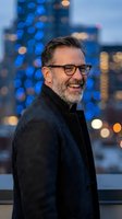 Confident middle-aged businessman with glasses smiling at urban evening cityscape with bokeh lights for corporate leadership and success concepts.