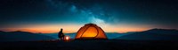 Panoramic night camping scene with illuminated orange tent and silhouette of person sitting by campfire under starry sky and mountain landscape at dusk.