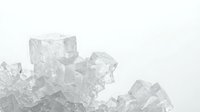 Clear ice cubes scattered on white background with water droplets and melting effects for beverage and cooling concepts.