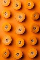 Fresh halved oranges arranged in rows on vibrant orange background creating modern minimal pattern composition for food and healthy lifestyle concepts.