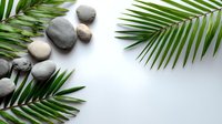 Zen spa composition with smooth gray stones and fresh green palm leaves on white background, creating minimalist wellness atmosphere.