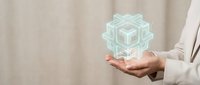 Professional businessman holding glowing holographic cube network symbol representing blockchain technology, digital transformation and innovation concepts.