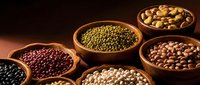 Assorted legumes and beans in wooden bowls on dark background, including lentils, chickpeas, and peas for cooking and nutrition.