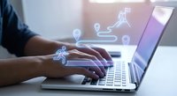 Professional working on laptop with digital logistics icons showing delivery truck and location pins for supply chain management and shipping solutions.