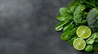 Fresh green vegetables and lime slices arranged on dark slate surface. Healthy eating, organic produce, and nutrition concept for culinary, wellness, and food styling projects.