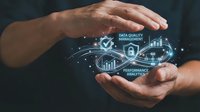 Hands protecting holographic data analytics icons with charts, graphs and security symbols representing digital business intelligence and information management.