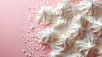 Delicate white meringue cookies scattered with sugar pearls on pink background, creating soft textured dessert composition for food photography and confectionery design.
