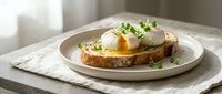 Poached eggs with runny yolks on toasted bread garnished with fresh microgreens served on white plate for healthy breakfast or brunch meal preparation.
