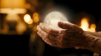 Elderly hands cupping a glowing orb of light against a warm fireplace background, symbolizing wisdom, hope, and spiritual energy.