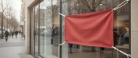 Red blank flag banner hanging on rope outside modern glass storefront for advertising mockup and promotional display purposes.