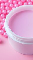 White cosmetic jar with pink moisturizer cream against blurred pink pearl background. Close-up view highlights product texture and packaging for beauty and skincare marketing.