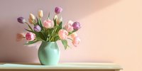 Elegant bouquet of pink and white tulips in mint green ceramic vase on wooden shelf against soft peach wall, creating serene spring atmosphere.
